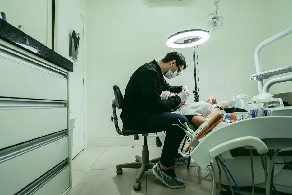 A dentist wearing a mask treats a patient in a modern dental clinic in Brazil.